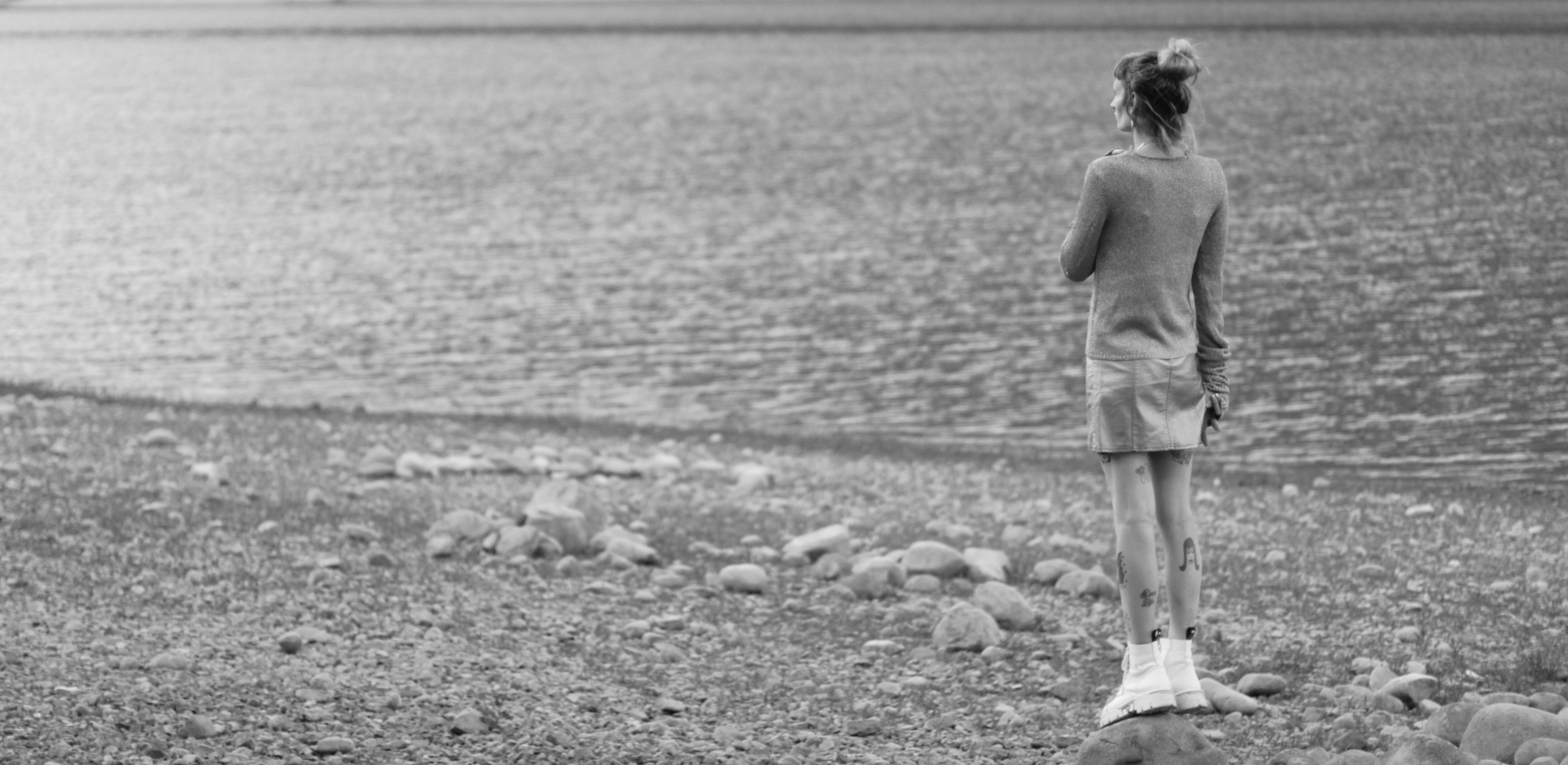 picture of a woman standing on a rock and watching a lake